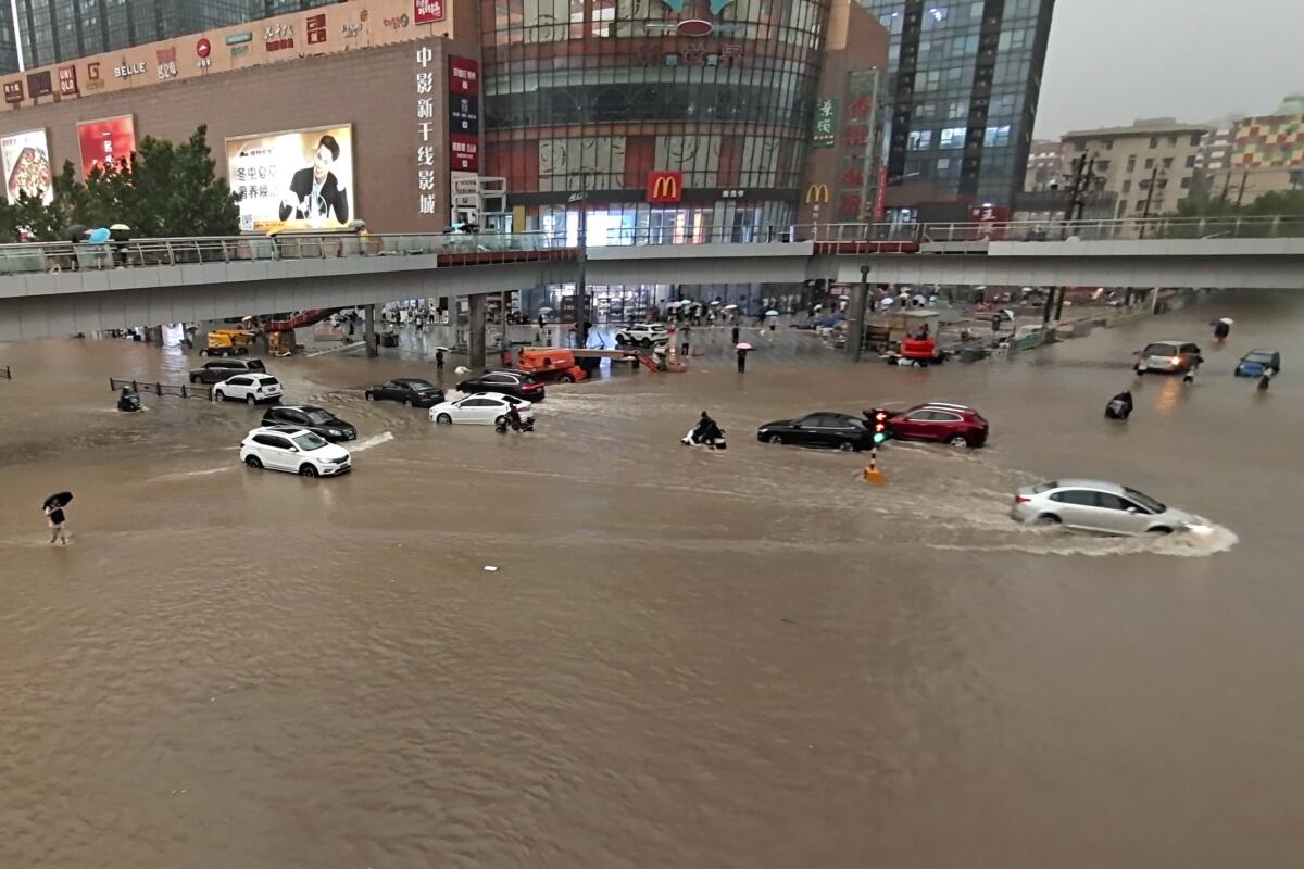 Vehicles are stranded in brown floodwater in Zhengzhou, China.