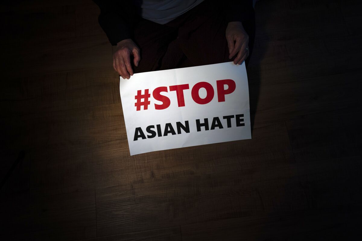 FILE - In this March 31, 2021, file photo, Jen Ho Lee, a 76-year-old South Korean immigrant, poses in her apartment in Los Angeles with a sign from a recent rally against anti-Asian hate crimes she attended. A new report released Thursday Aug. 12 has found the frequency of anti-Asian incidents, from taunts to outright assaults, reported in the United States so far this year seems poised to surpass last year despite months of political and social activism. (AP Photo/Jae C. Hong, File)