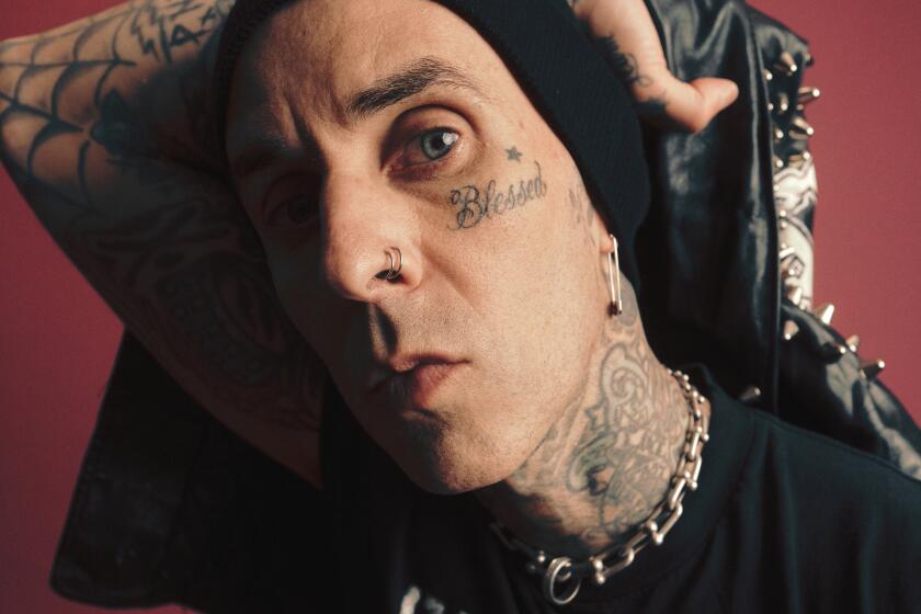 Travis Barker peers into the camera lens with his arm over his head