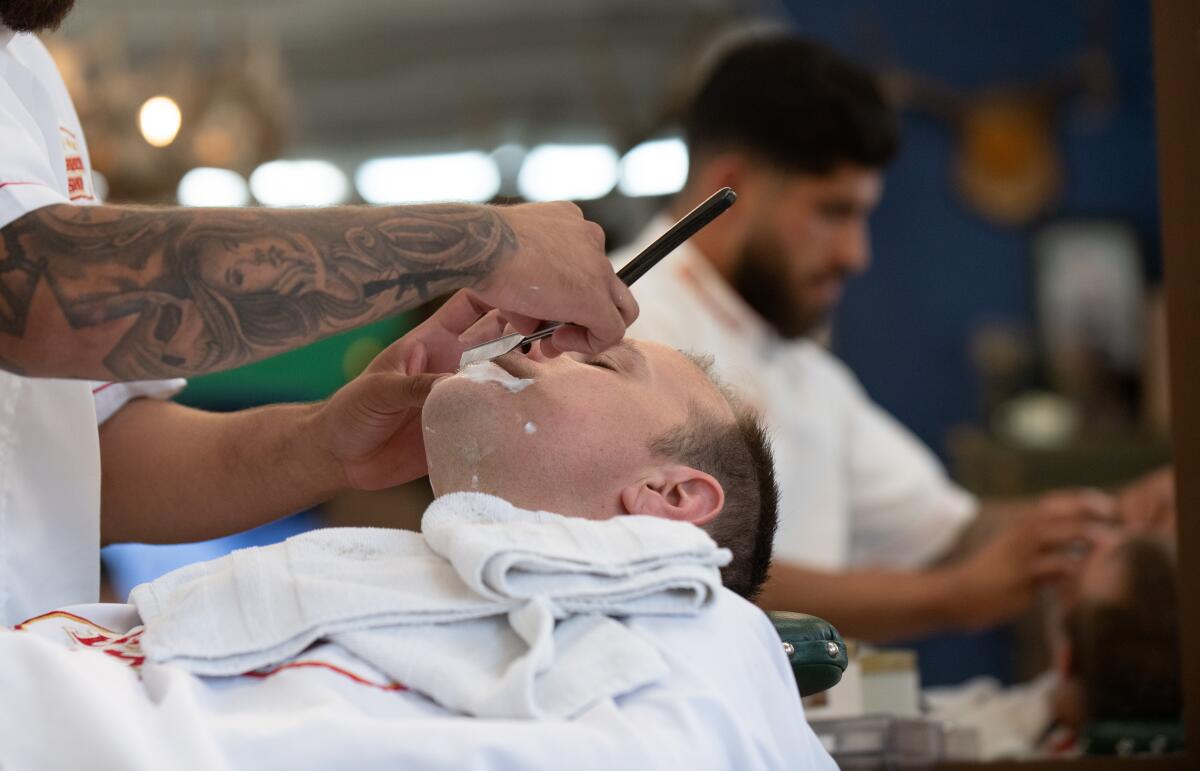 Sam Burst gets a straight-razor shave from Edward Mugica at American Barbershop in Orange on Thursday.