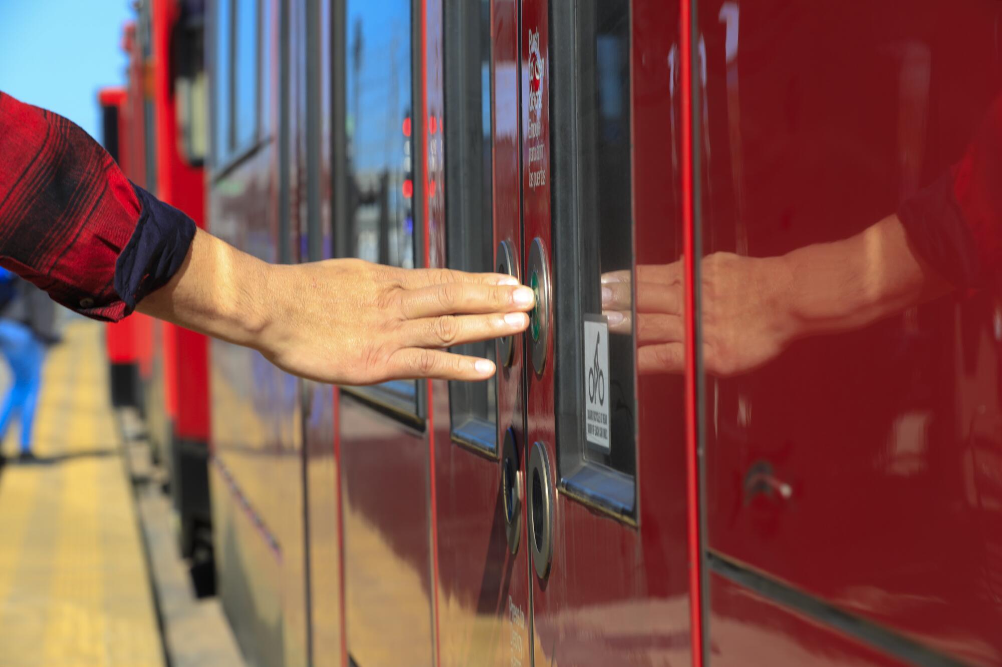 A passenger pushes the door button of trolley train heading east from the Old Town station on Thursday morning, December 19, 2019.