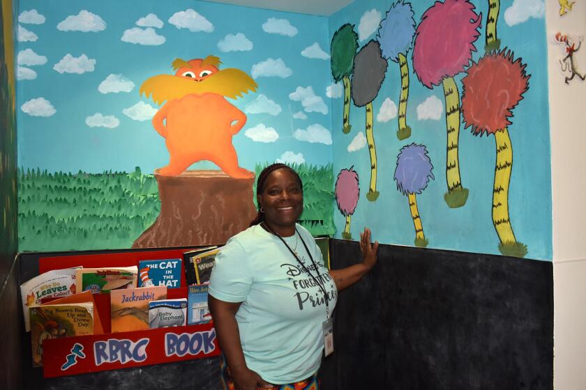Tonya Thomas standing in the book nook she created for young children several years ago when she was assistant director.