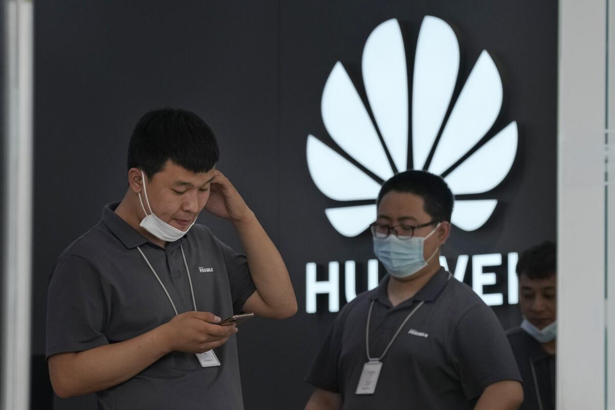 Huawei store workers wait for customers in Beijing on Wednesday, June 2, 2021. Huawei is launching its own HarmonyOS mobile operating system on its handsets as it adapts to losing access to Google mobile services two years ago after the U.S. put the Chinese telecommunications company on a trade blacklist. (AP Photo/Ng Han Guan)
