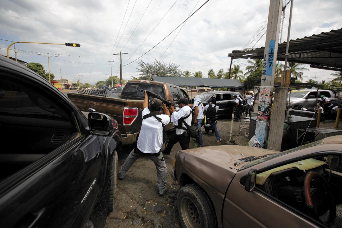 "Self-defense" militia fighters engage in a battle with suspected Knights Templar drug cartel members in Nueva Italia, Mexico. The vigilantes, now backed by federal police, have taken control of the town.