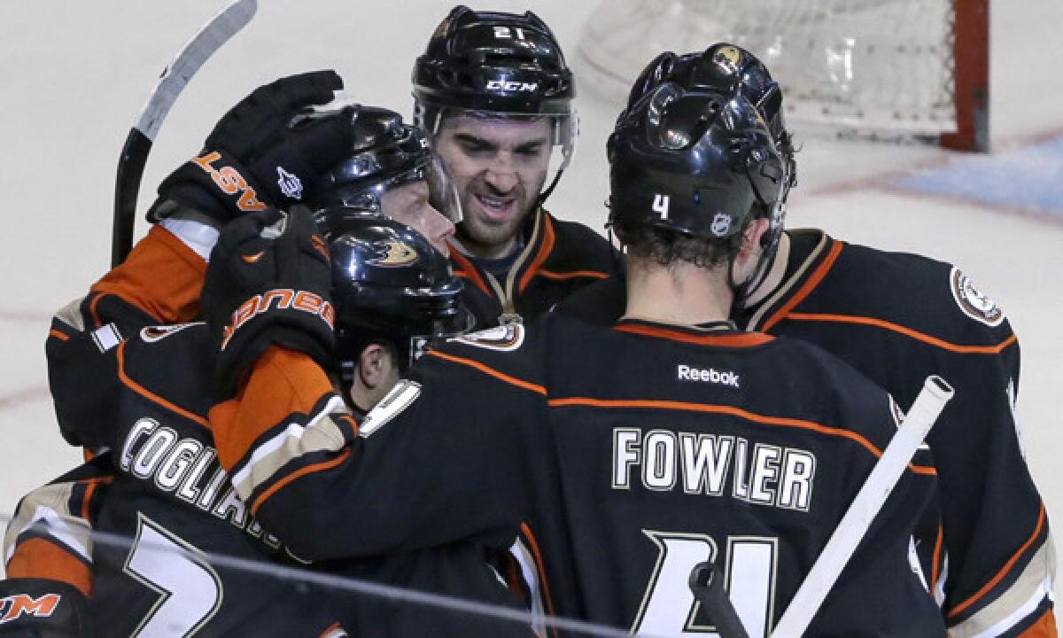 Ducks players celebrate a goal by center Andrew Cogliano, bottom left, during their 1-0 win over the Detroit Red Wings on Sunday.
