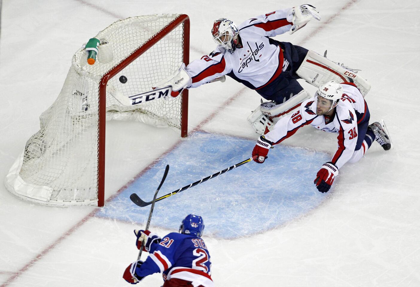 New York Rangers center Derek Stepan shoots and scores on Washington Capitals goalie Braden Holtby in front of Capitals defenseman Jack Hillen during third period action in Game 4 of their NHL Stanley Cup playoffs Eastern Conference Quarterfinal hockey gam
