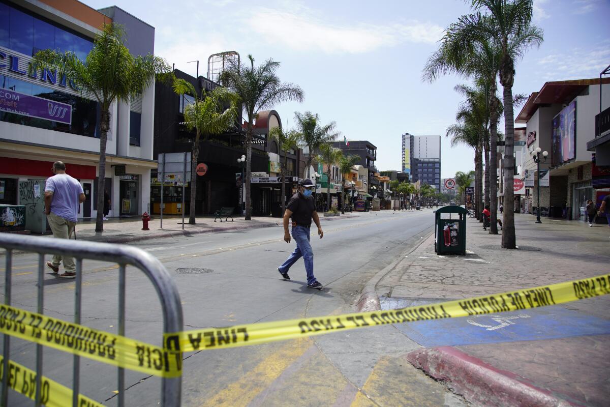 A masked person crosses a road near police tape.