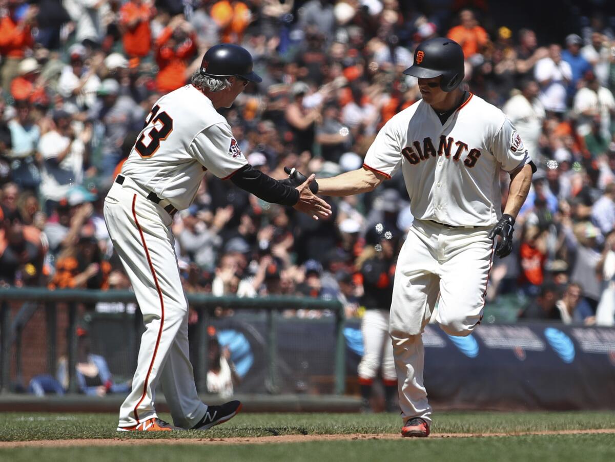 Nick Hundley, de los Gigantes de San Francisco, recibe la felicitación del coach de la antesala Ron Wotus, luego de conectar un jonrón en el duelo ante los Padres de San Diego, el miércoles 2 de mayo de 2018.