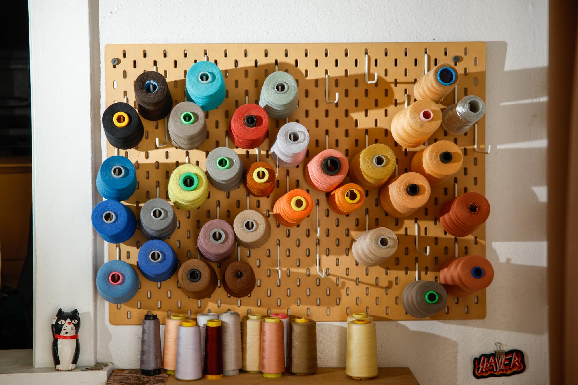 Spools of thread hang in the wall in artist Erick Medel's studio