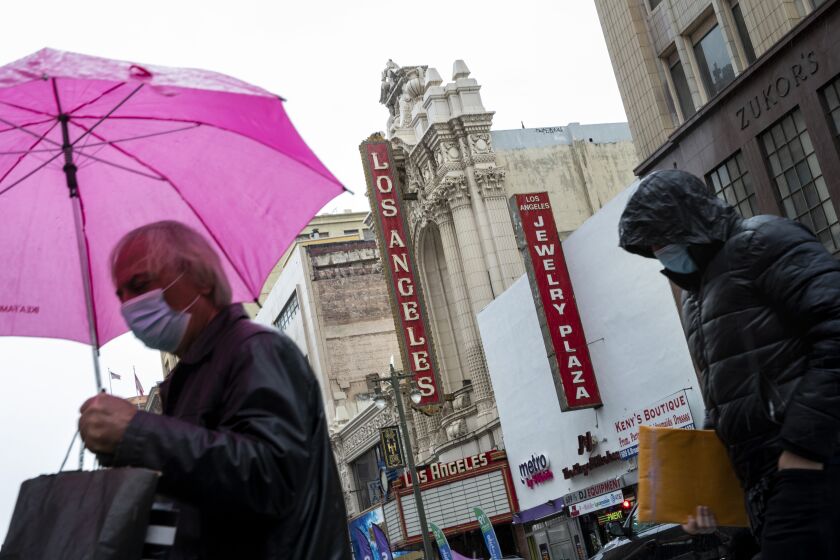 Los Angeles, CA - February 04: People had to break out their umbrellas while walking along Broadway, in downtown Los Angeles, CA, as a storm hit, Thursday, Feb. 4, 2021. (Jay L. Clendenin / Los Angeles Times)