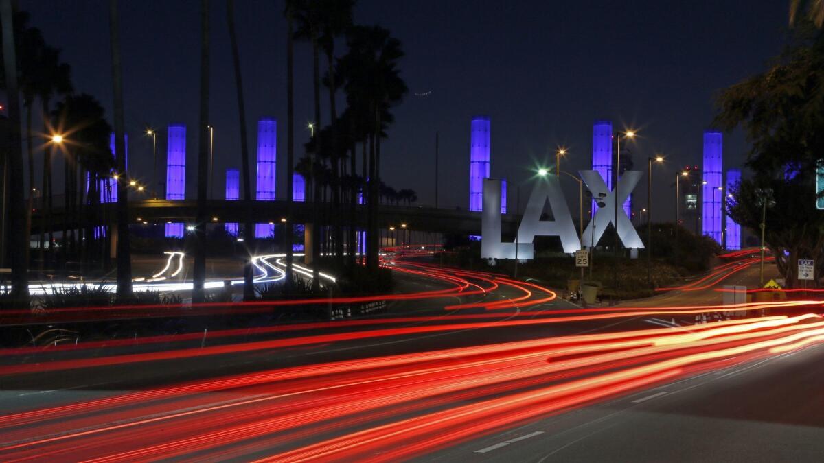 Lighted pylons and cars create a light show on Century Boulevard, near the entrance to Los Angeles International Airport. The airport plans to install new technology in a bathroom at Terminal 4 to help keep them cleaner and notify passengers when a stall is vacant.