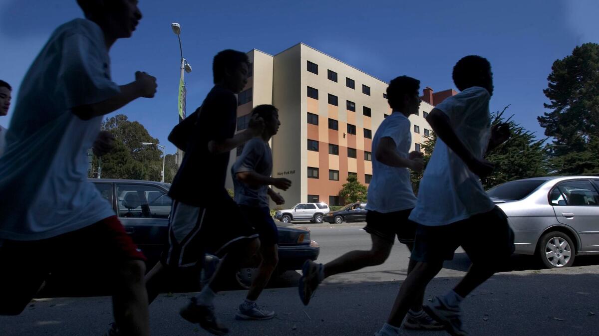 A group of athletes runs past Mary Park Hall at San Francisco State University.