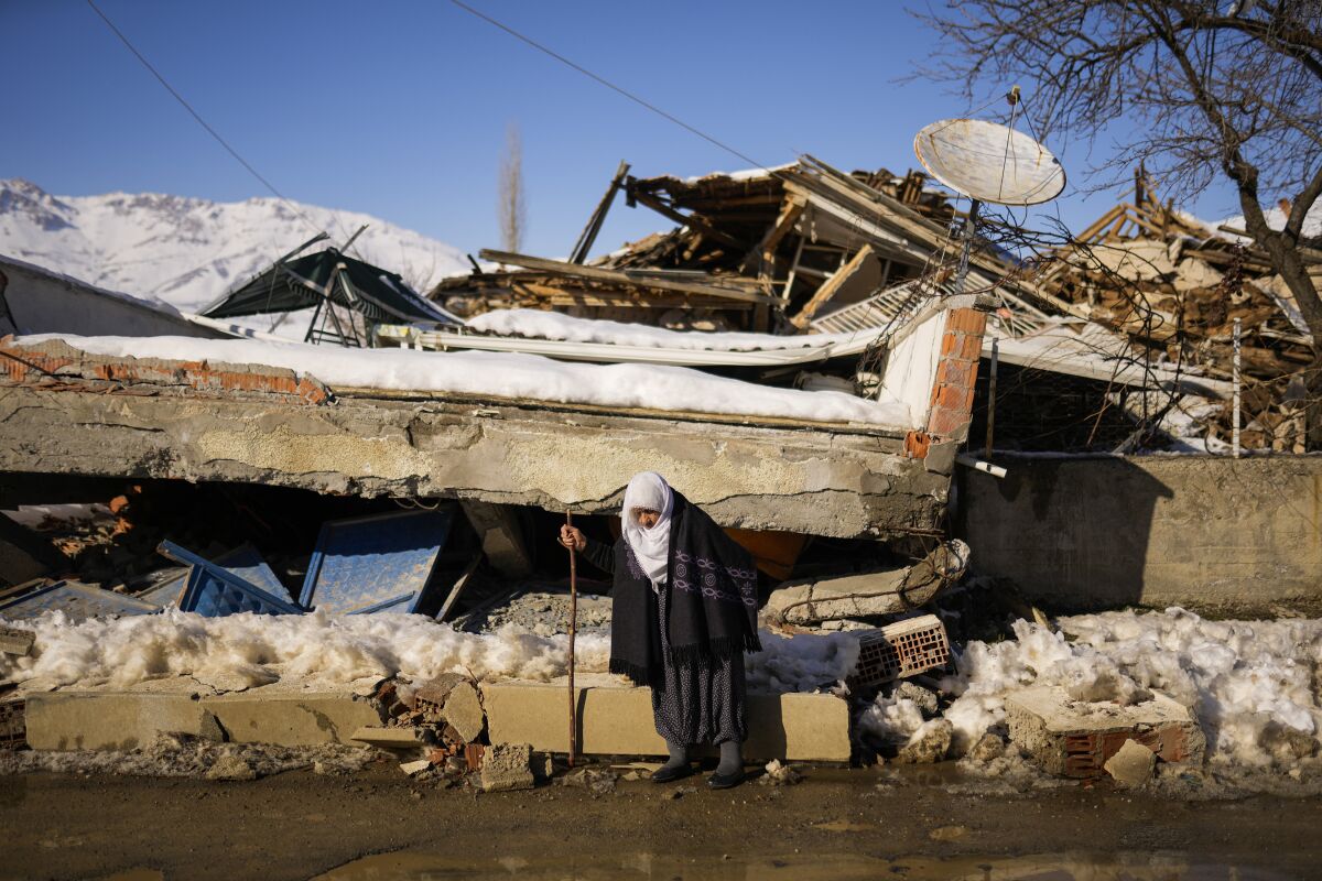 Woman walking past a house destroyed earthquake