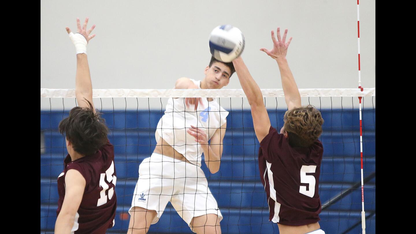 Corona Del Mar's Kevin Kobrine, 4, kills the ball past two Laguna Beach blockers in boys nonleague volleyball action on Tuesday.