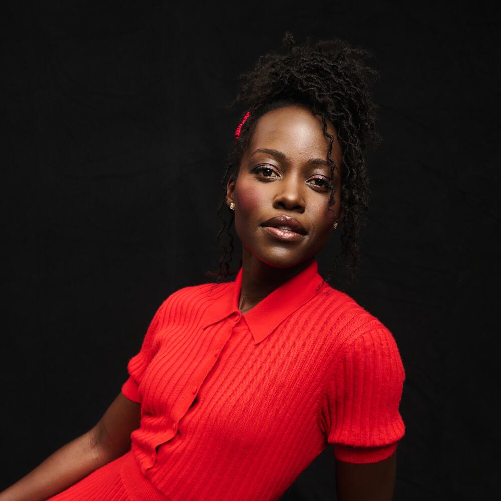 A woman in a red dress gazes at the lens.