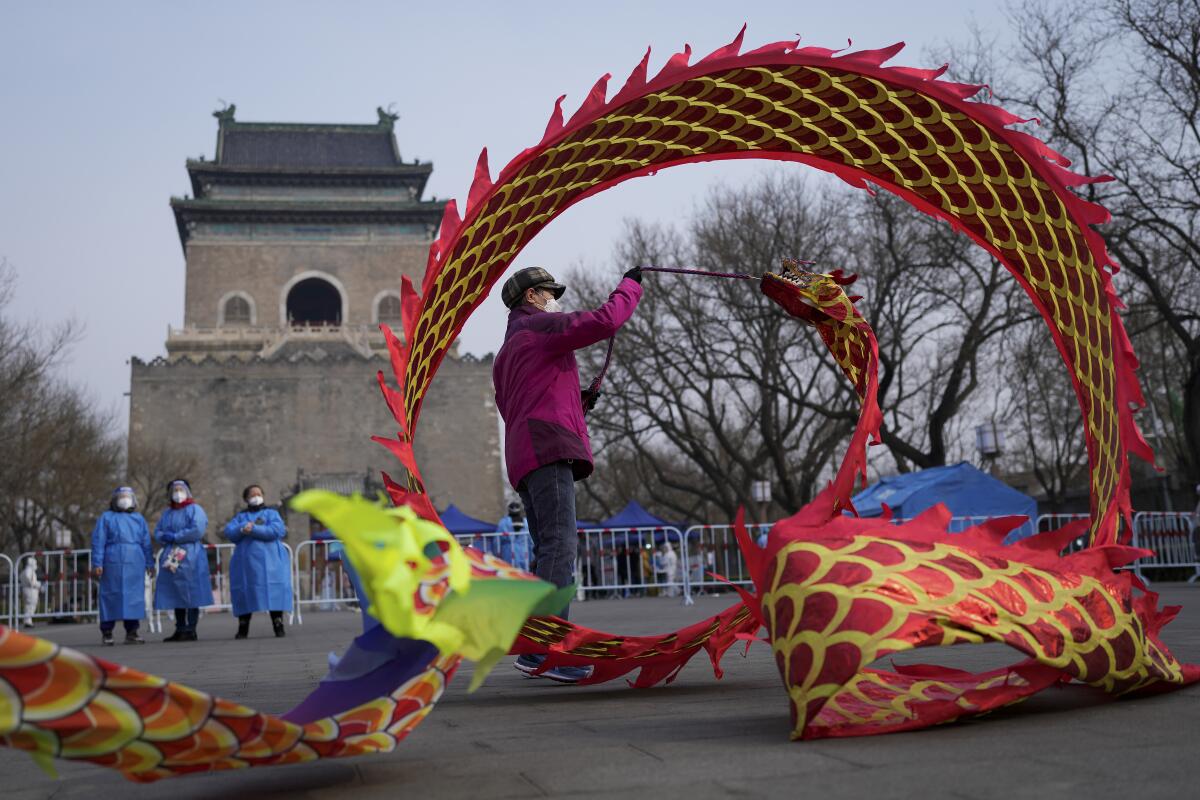 A masked resident twirls a dragon-shaped ribbon near a barricaded coronavirus testing site in Beijing. 