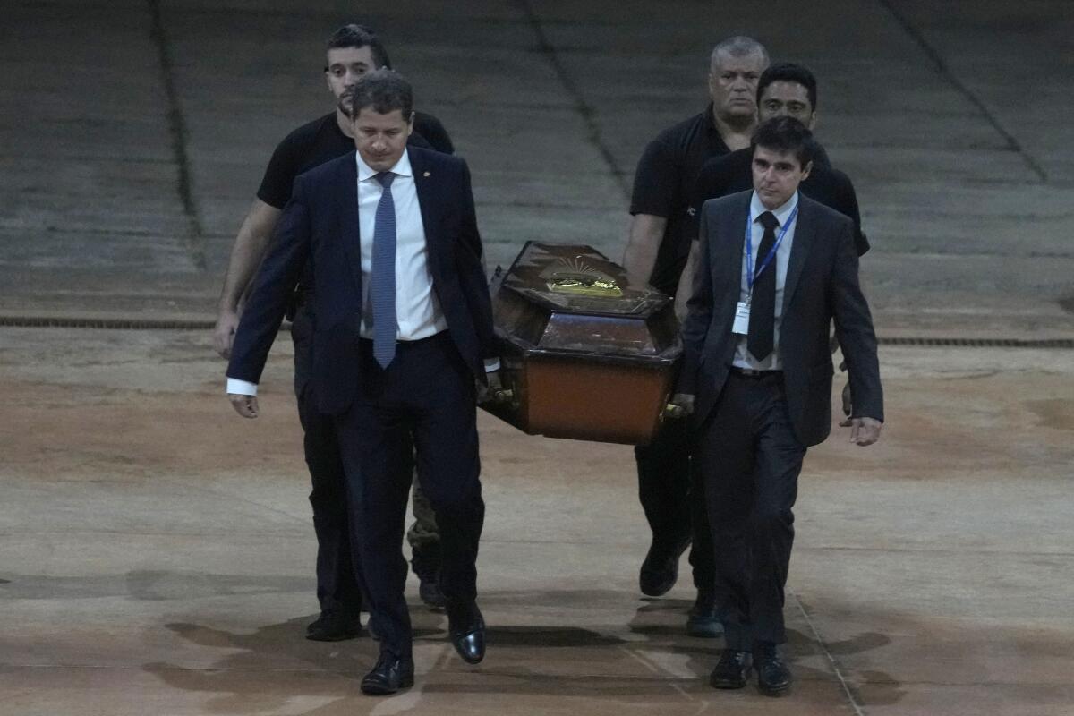 Federal police officers walk with a coffin.