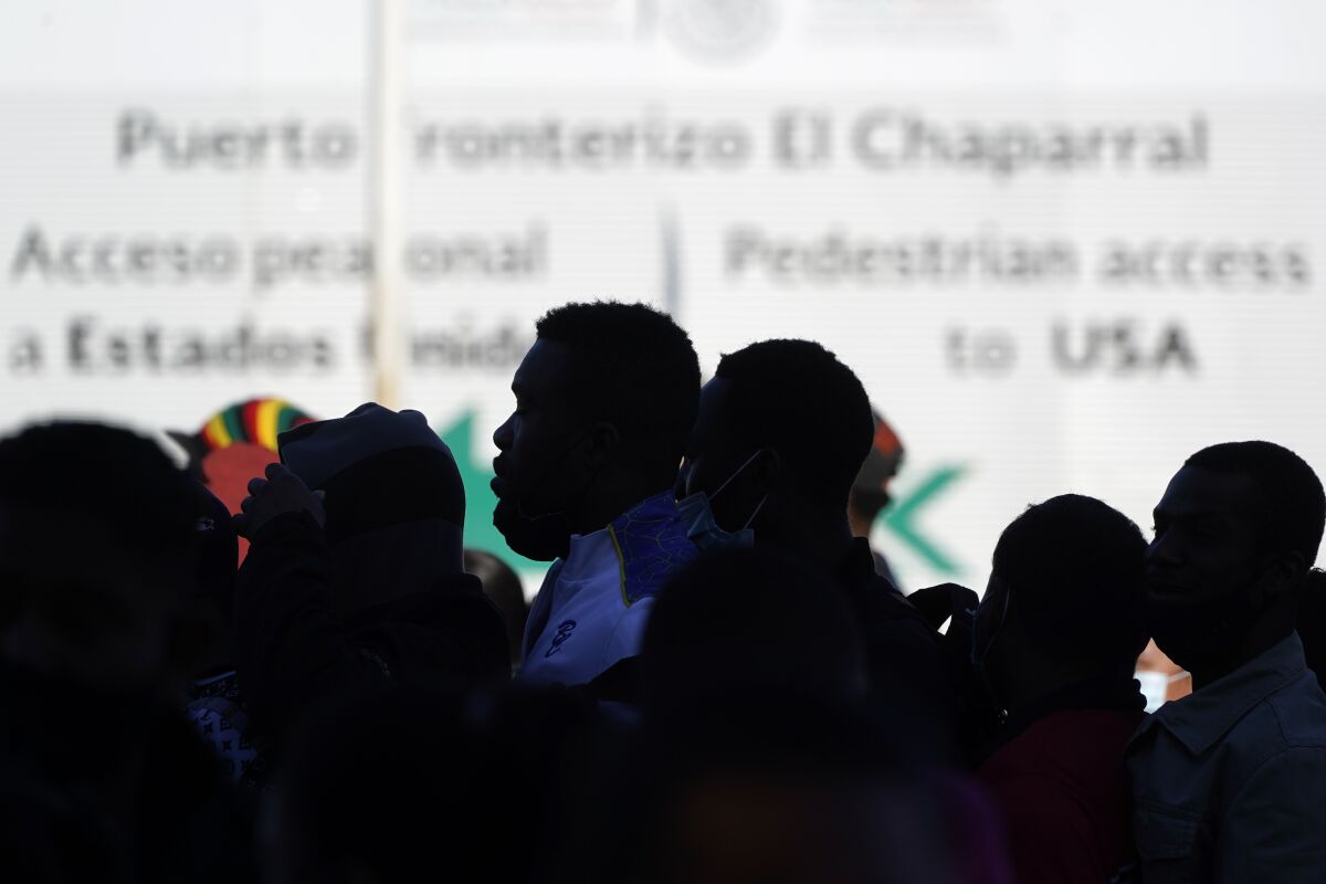 Asylum seekers waiting in Mexico stand in line at the border.