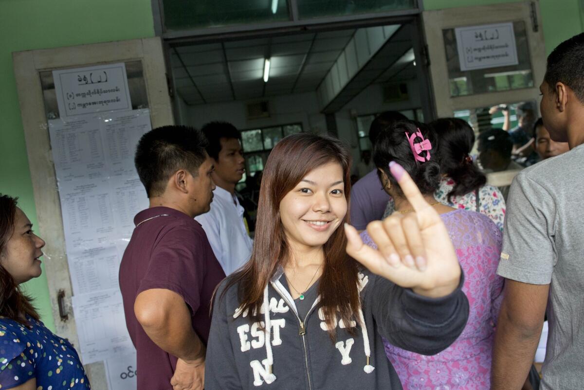 A voter shows her finger marked with ink, indicating she cast a ballot, at a polling station in Yangon, Myanmar.