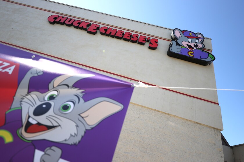 A sign with an animated mouse is posted outside a Chuck E. Cheese restaurant.