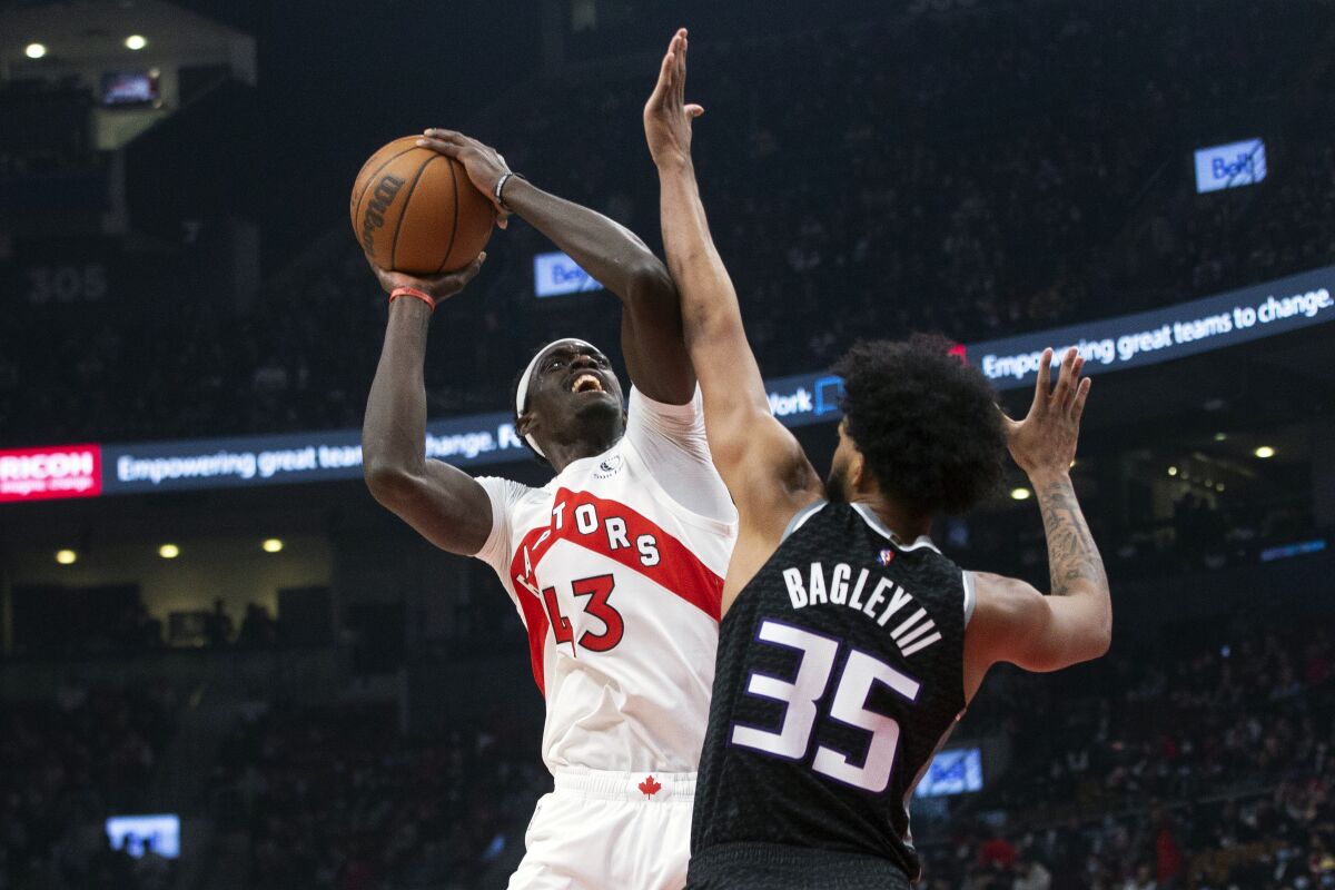 Toronto Raptors' Pascal Siakam, left, scores on Sacramento Kings' Marvin Bagley III during the first half of an NBA basketball game in Toronto, Monday, Dec. 13, 2021. (Chris Young/The Canadian Press via AP)