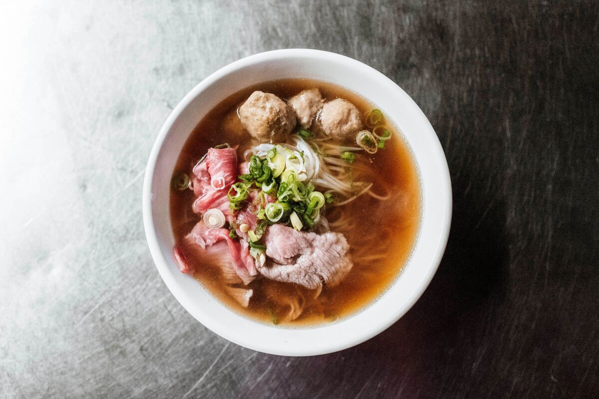 An overhead photo of a bowl of beef pho against a silver tabletop.