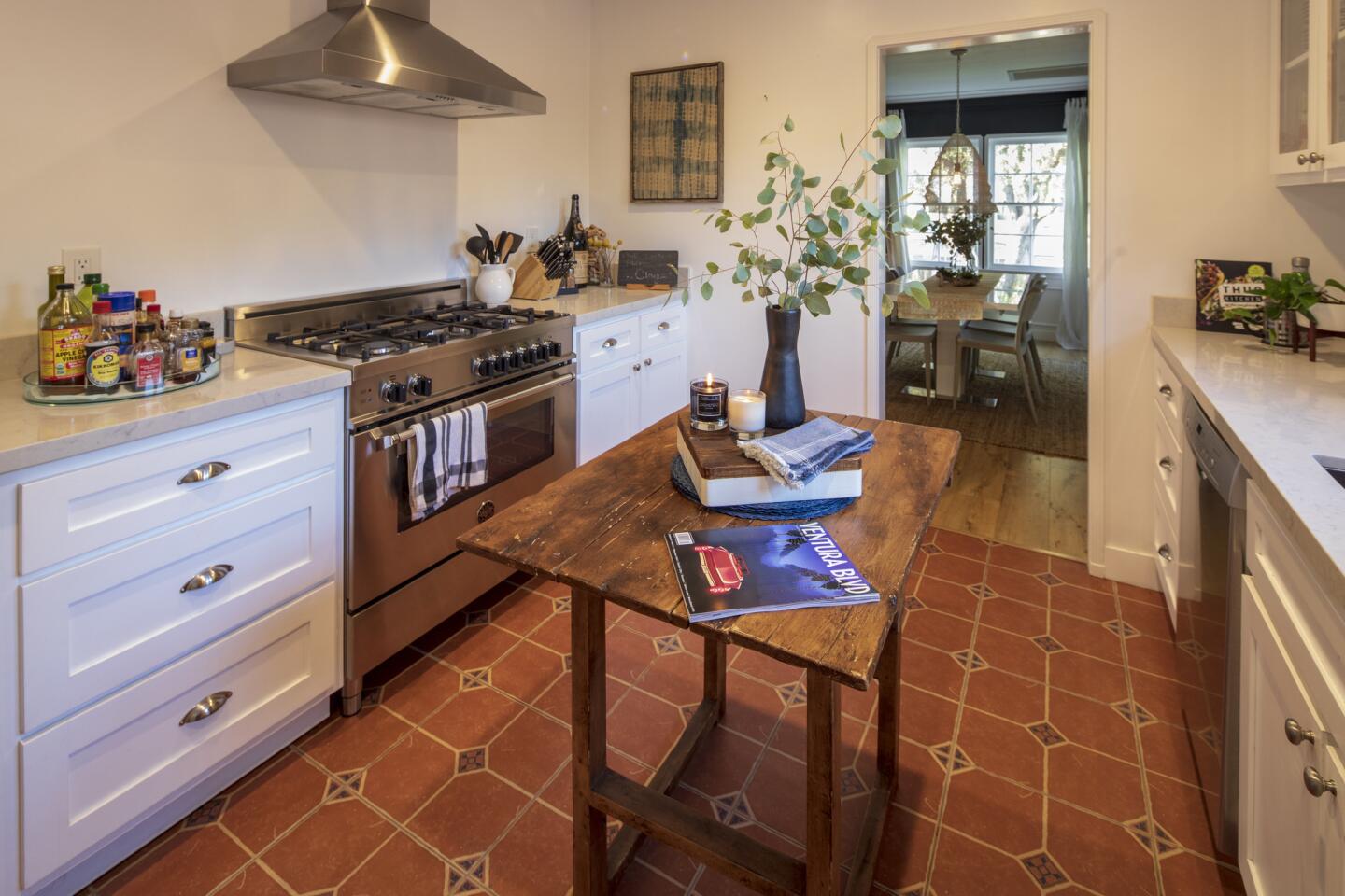 In the galley kitchen, Leiaghat preserved the windows and charming Spanish floor tile and removed the appliances and shelving. “I wanted to make it clean and easy and user--friendly,” he says of the kitchen. True to his love of vintage, Sam uses an antique dining table as a kitchen island.