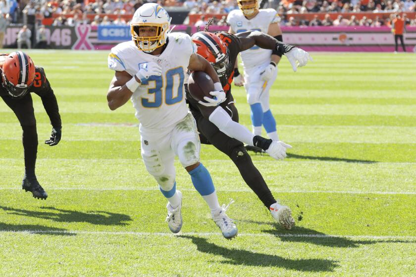 Los Angeles Chargers running back Austin Ekeler (30) stays ahead of Cleveland Browns defensive end Jadeveon Clowney (90) as he runs the ball in for a touchdown during the first half of an NFL football game, Sunday, Oct. 9, 2022, in Cleveland. (AP Photo/Ron Schwane)
