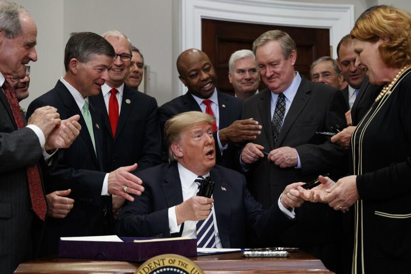 President Donald Trump hands out pens after signing the "Economic Growth, Regulatory Relief, and Consumer Protection Act," in the Roosevelt Room of the White House, Thursday, May 24, 2018, in Washington (AP Photo/Evan Vucci)