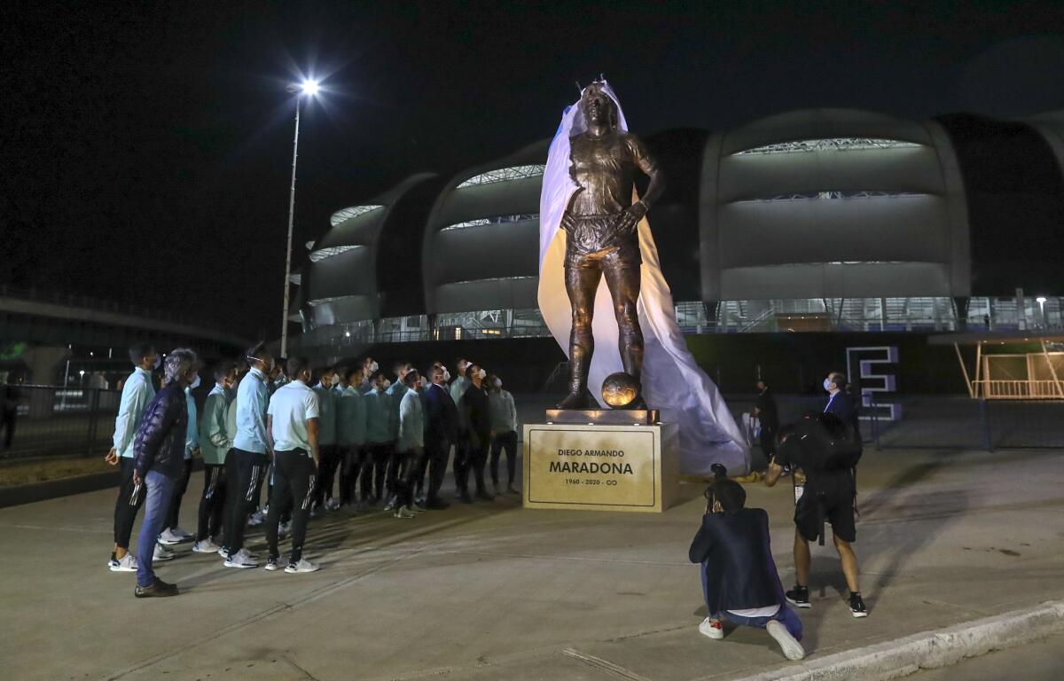 Jugadores de la selección argentina presencian la develación de una estatua de Diego Maradona.