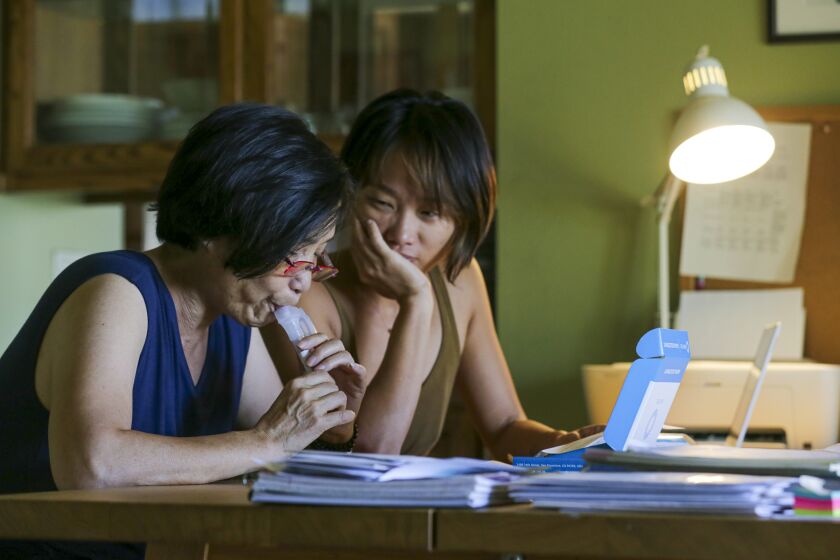 BRADBURY, CA - SEPTEMBER 30: Yi Luo, 37, right, watches her 63-year-old mother Yuyuan Lin, diagnosed with stage three breast cancer, collect saliva specimen for a DNA test on Wednesday, Sept. 30, 2020 in Bradbury, CA. (Irfan Khan / Los Angeles Times)