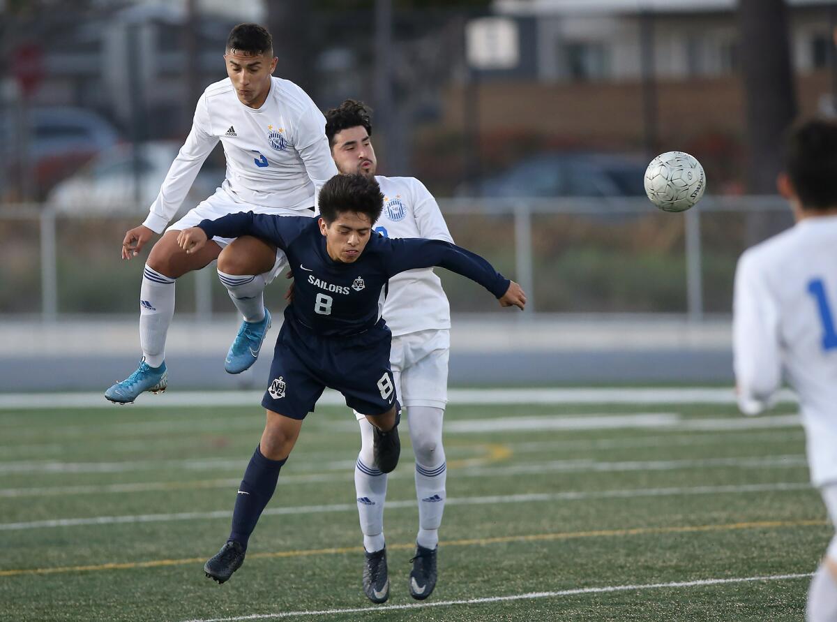 Newport Harbor’s Yamil Razo (8) is bumped by La Habra’s Cristian Reyes (3) and Ryan Morales as they go for the ball in the second round of the CIF Southern Section Division 2 playoffs on Friday in Newport Beach.