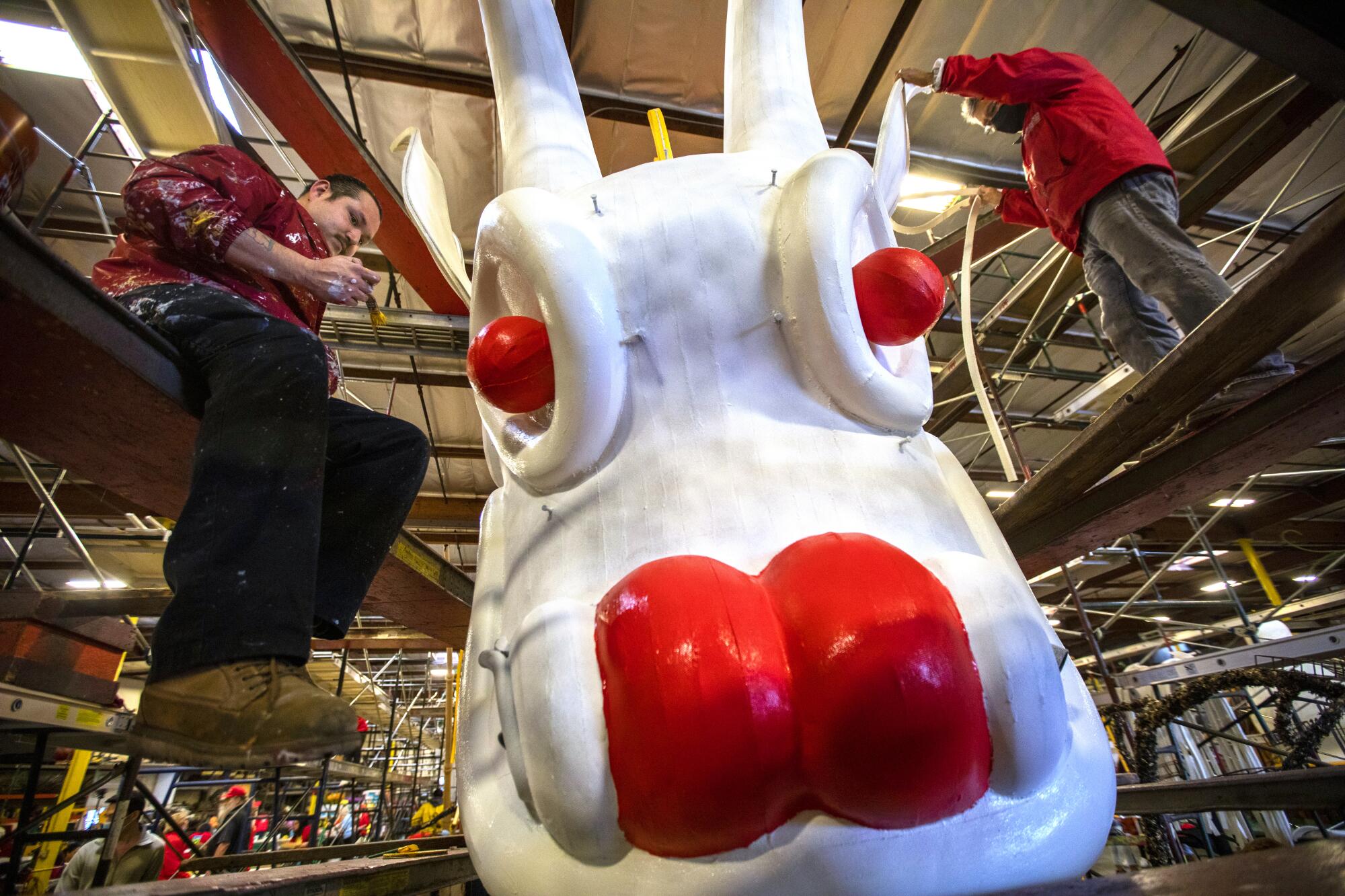  Two men work on a float's gigantic head of a white and red Chinese dragon 