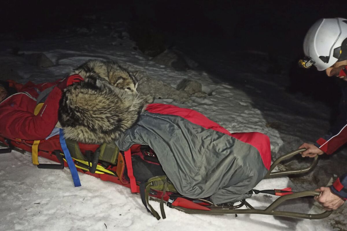 This photo provided by Croatian Mountain Rescue Service shows a hiker and his dog during a rescue operation at Mount Velebit, in Croatia on Saturday, Jan. 1, 2022. Croatian rescuers are praising a dog who protected his injured owner from freezing high on a snowy mountain, keeping him warm for 13 hours in the dark until he could get medical attention. “Friendship and love between man and dog know no boundaries,” the county’s mountain rescue service wrote on Twitter Tuesday. The accident occurred late on Jan. 1 more than 1,700 meters (5,600 feet) up Mount Velebit, that stretches along Croatia’s Adriatic Sea coast. (Croatian Mountain Rescue Service via AP)
