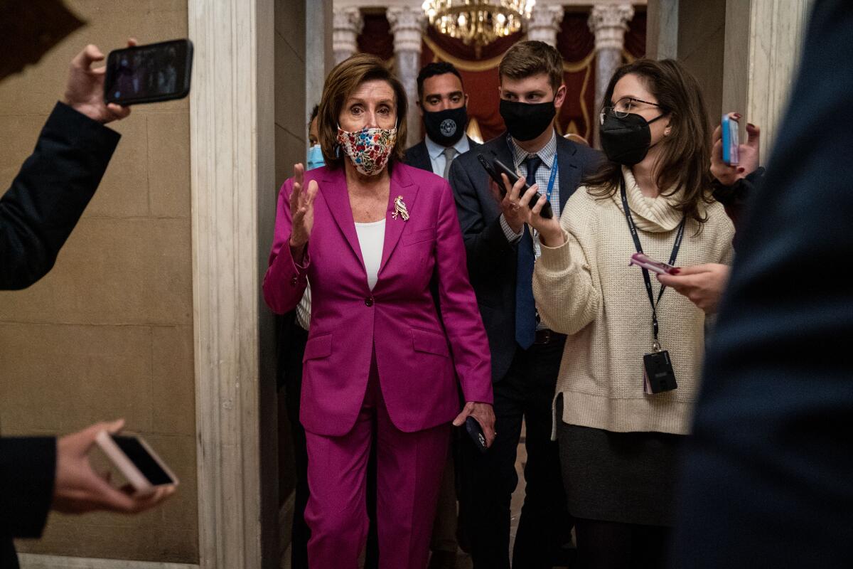 A masked Nancy Pelosi answers questions from reporters.