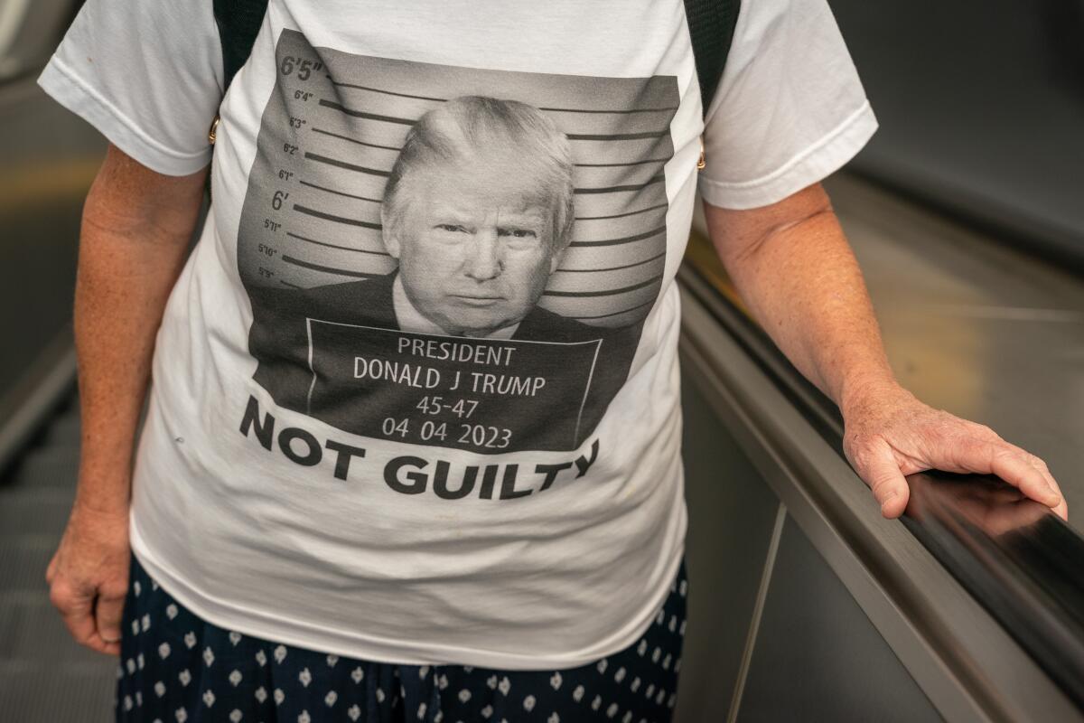 A person wears a T-shirt with a mug shot of former President Trump.