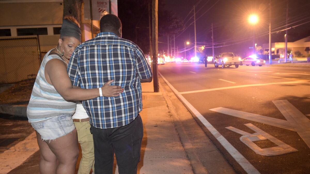 Bystanders wait down the street after a mass shooting at the Pulse nightclub in Orlando, Fla.
