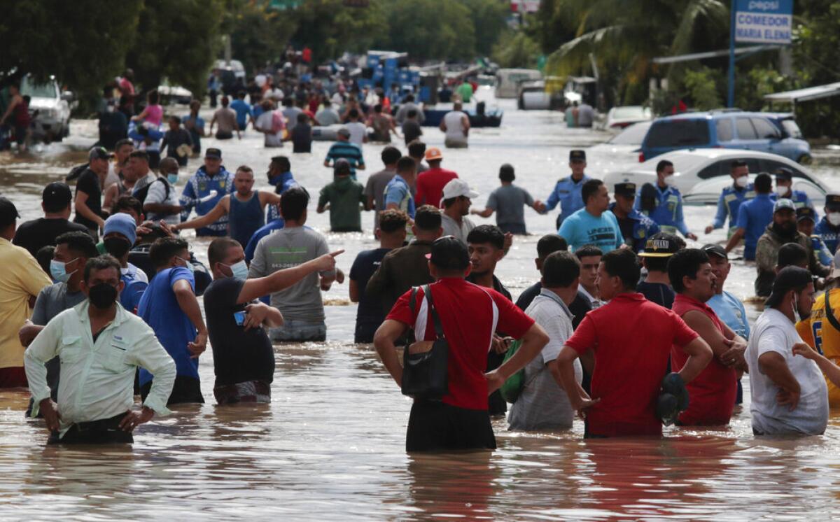 Múltiples personas vadean un camino inundado tras el paso del huracán Eta, 