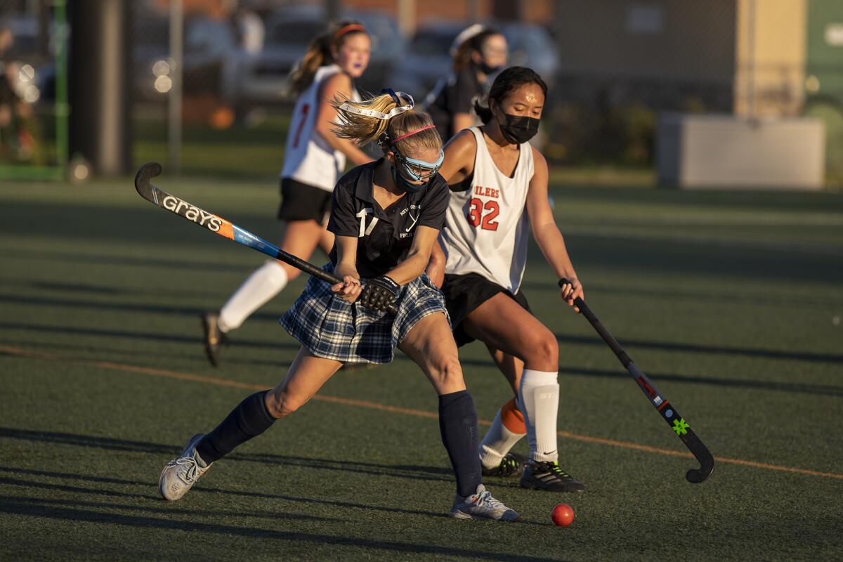 Newport Harbor's Zoe Bixby and Huntington Beach's Niki Serrano battle for a ball during a field hockey match on Friday.