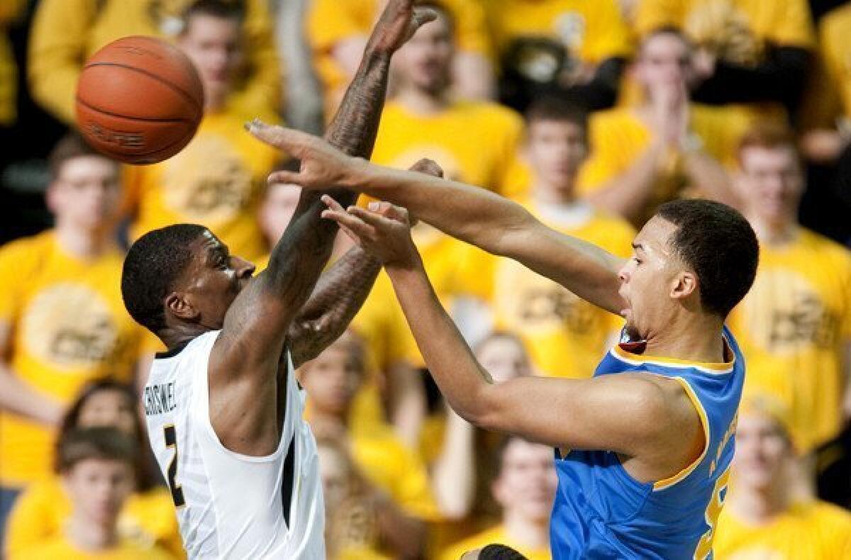 UCLA guard Kyle Anderson, right, passes the ball around Missouri forward Tony Criswell in the first half Saturday.