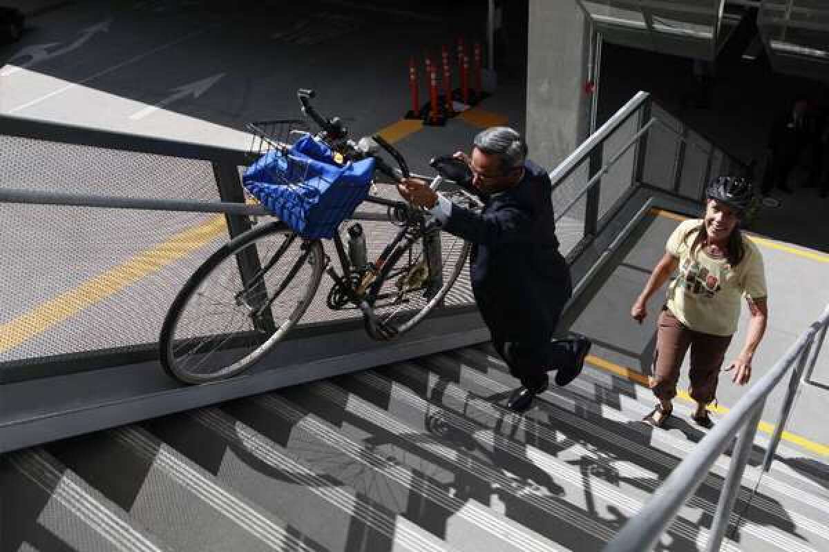Roland Cordero, director of facilities at Foothill Transit, shows Alice Strong how to use the bike rail to ascend the stairs at the El Monte bus station. Millennials prefer close-in living that is more conducive to using bikes for transportation over long car commutes, which has serious implications for future transportation funding, a new report says.