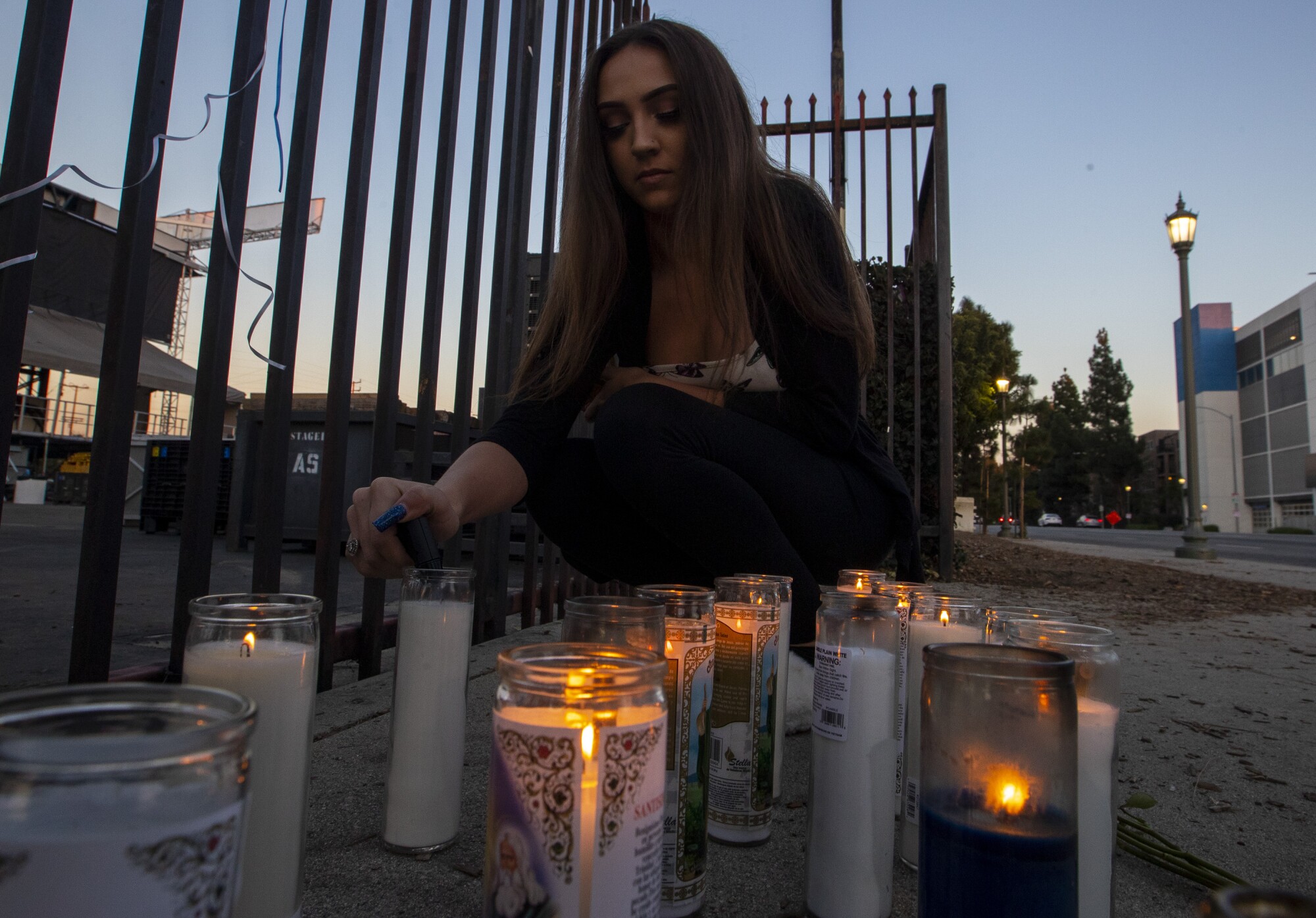 A woman lights a candle in honor of slain rapper Drakeo the Ruler on Dec. 19, 2021.