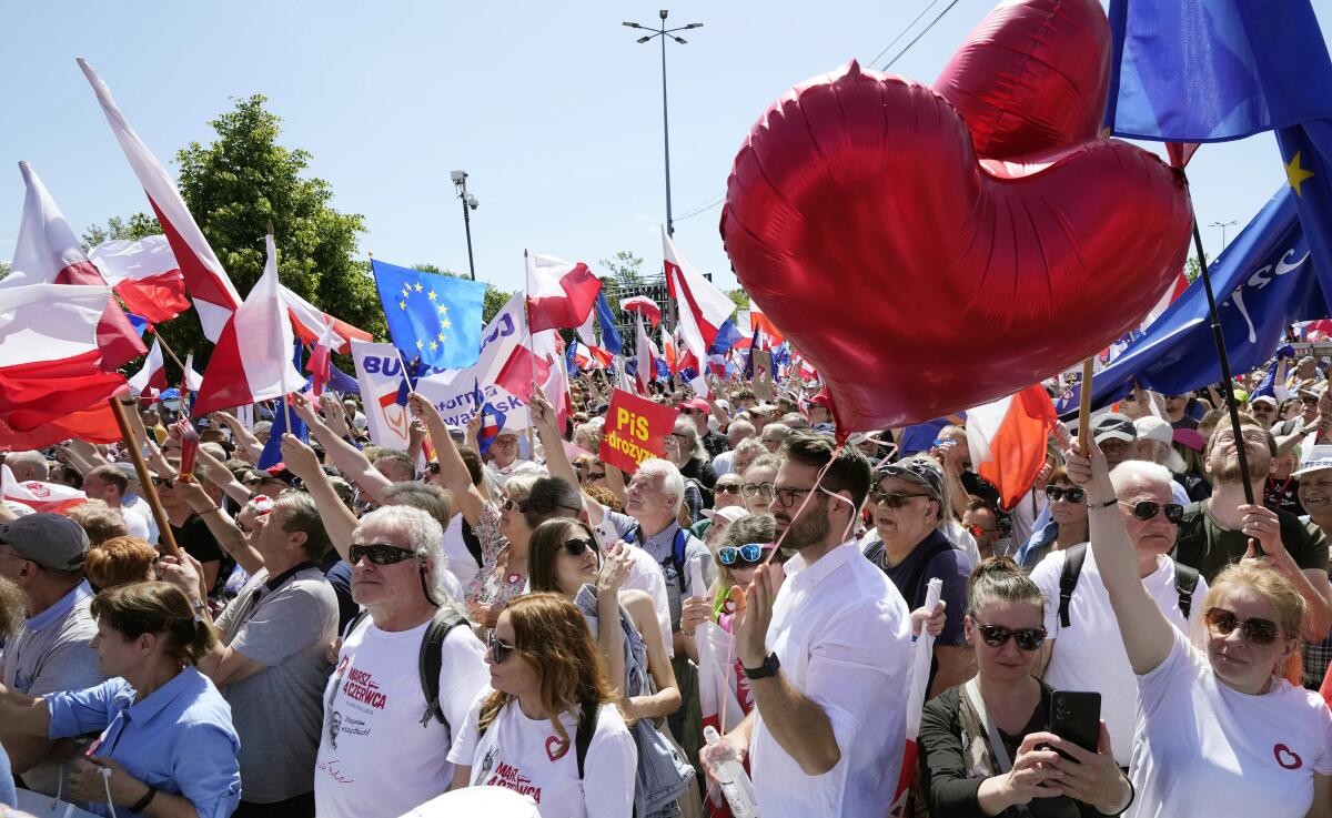 A crowd of demonstrators marching and carrying flags and heart-shaped balloons.