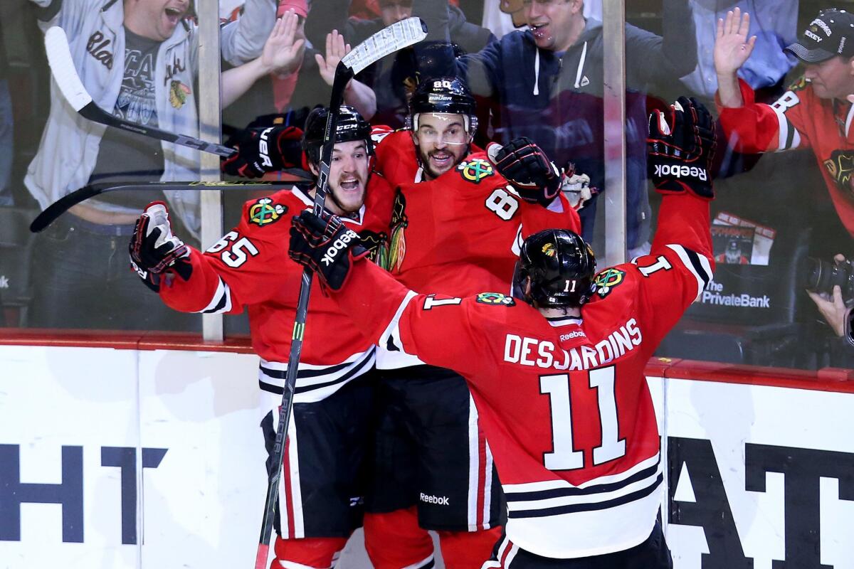 Blackhawks winger Andrew Shaw (65) celebrates with teammates Antoine Vermette and Andrew Desjardins after scoring against the Ducks in the third period of Game 6.