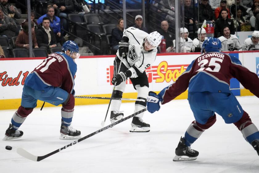 Los Angeles Kings right wing Adrian Kempe, center, fires the puck between Colorado Avalanche center Andrew Cogliano, left, and right wing Logan O'Connor in the second period of an NHL hockey game Thursday, March 9, 2023, in Denver. (AP Photo/David Zalubowski)