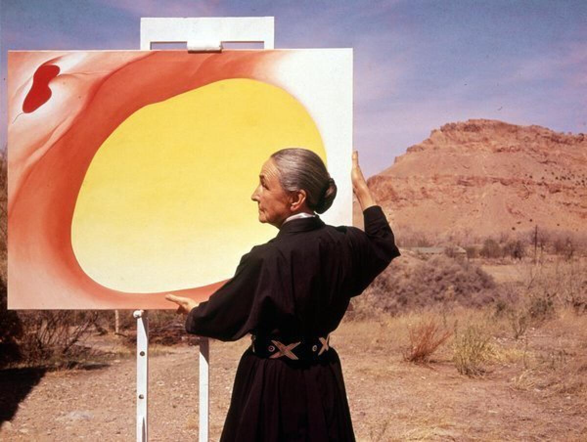 American artist Georgia O'Keeffe adjusts a canvas from her "Pelvis Series: Red With Yellow." A new tour of her home in Abiquiu, N.M., gives visitors unusual access.