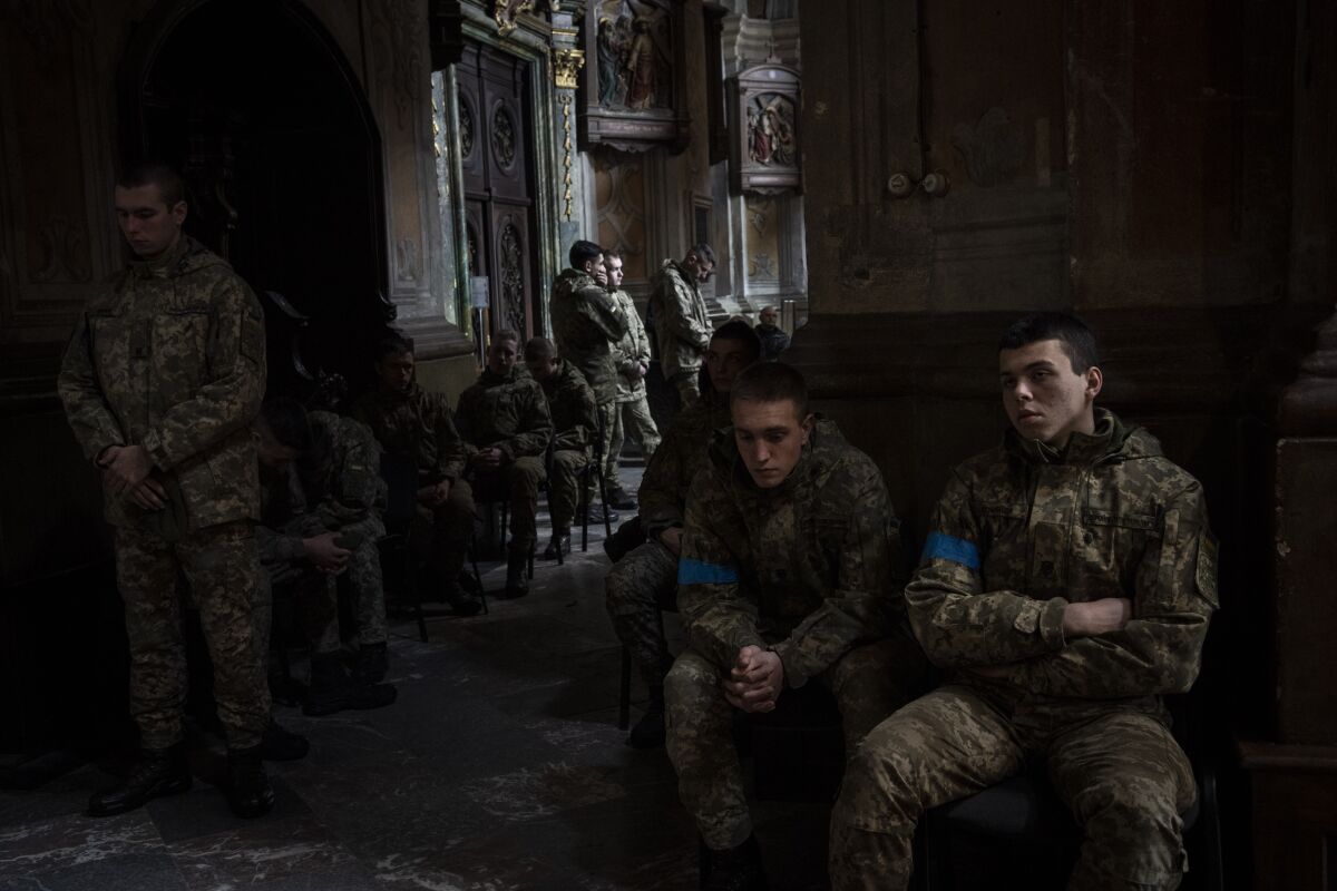 Military cadets attend a funeral ceremony for four of the Ukrainian military servicemen, who were killed during an airstrike in a military base in Yarokiv, in a church in Lviv, Ukraine, Tuesday, March 15, 2022. At least 35 people were killed and many wounded in Sunday's Russian missile strike on a military training base near Ukraine's western border with NATO member Poland. (AP Photo/Bernat Armangue)