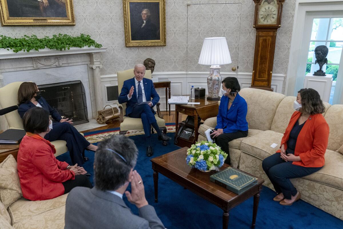 Biden speaks as he, Harris and four others are seated on couches and chairs in the Oval Office.
