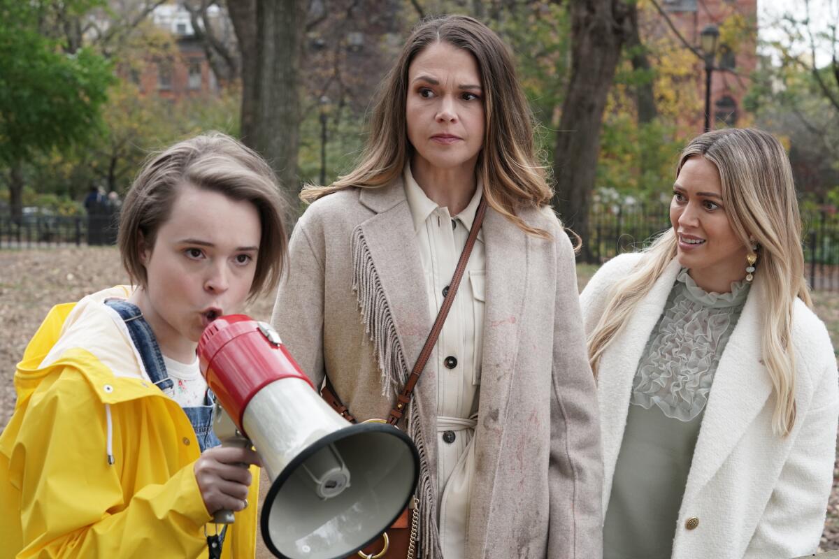 Füpa Grünhof, with a megaphone as a Greta Thunberg-like character, beside skeptical Sutton Foster and Hilary Duff.