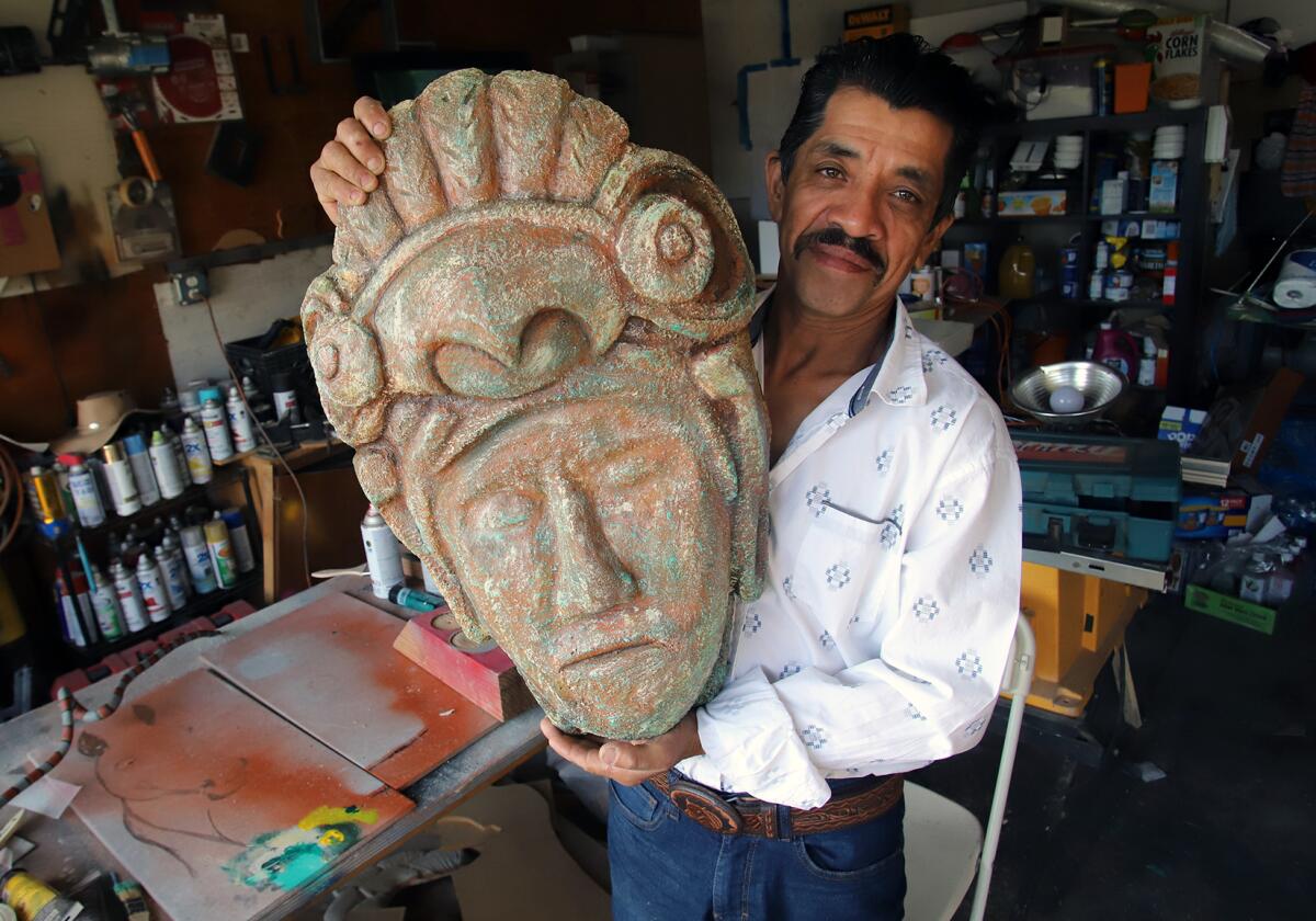 El artista guatemalteco muestra una escultura de cemento en forma de máscara con la figura del guerrero maya Tecun Umán.